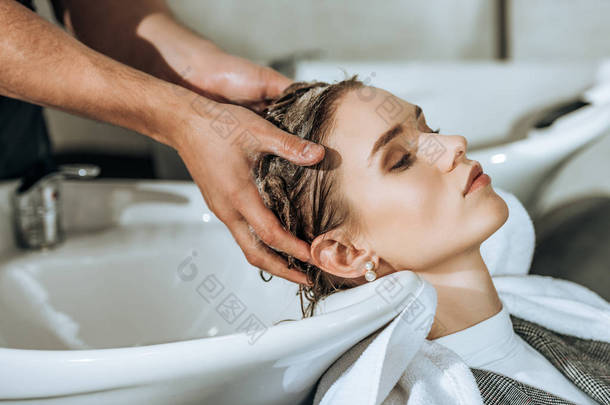 部分看法发型师洗头对有吸引力的年轻女子在美容院  