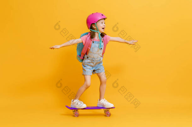 童年和快乐的时光！可爱的孩子与滑板上的彩色纸墙背景。带背包的<strong>小孩</strong>准备学习的女孩.