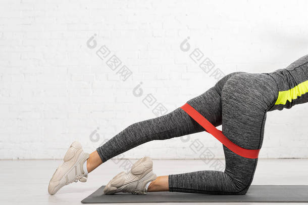有运动能力的妇女跪在膝上，与阻力带一起锻炼的剪影