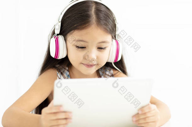 微笑的女孩在<strong>耳机</strong>和使用平板<strong>电脑</strong> 