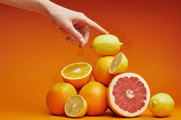 裁剪拍摄的人触摸堆新鲜成熟的柑橘水果橙色