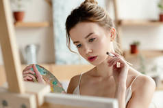有吸引力的女孩与刷子和调色板绘画图片在艺术工作室