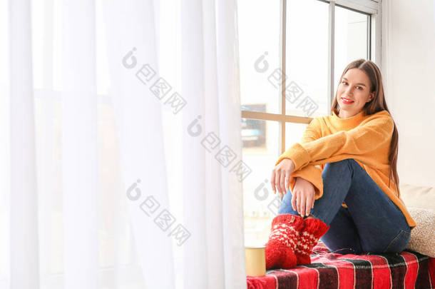 穿着冬衣的年轻女子坐在窗台上