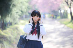 日本学校女孩礼服与樱花自然走道