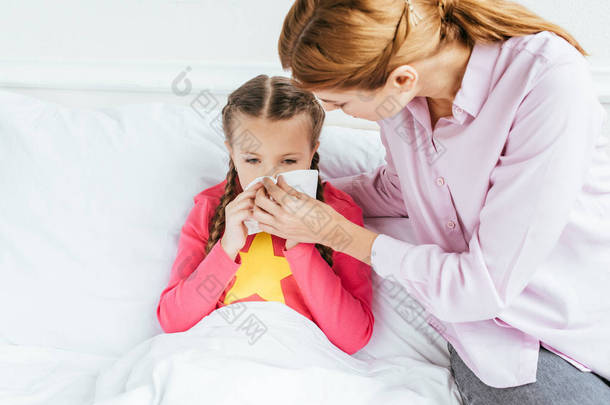 忧心忡忡的母亲把餐巾送给流鼻涕的生病的女儿 