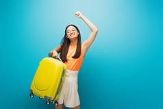 戴眼镜、头戴黄色行李、头戴蓝色标志的快乐的亚洲女人 