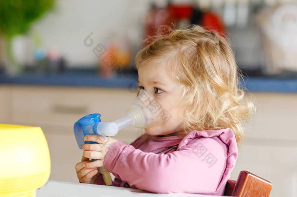 小<strong>女孩</strong>蹒跚学步，在家里用雾气吸入。父亲或母亲帮助和保持装置。患流感、咳嗽和支气管炎的儿童.哮喘吸入器吸入蒸汽病概念