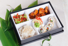 寿司商务午餐盒里，三文鱼烧滚芝麻、 大米、 芥末、 腌的姜顶上，竹叶孤立、 白色背景