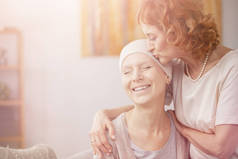 高级红头发的女人亲吻她快乐的癌症病的妹妹额头的明亮照片