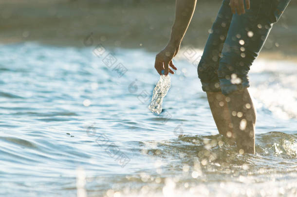 义工从海里捡塑料瓶垃圾. 从下面看,海浪,日落,水花. 清洁海洋概念. 