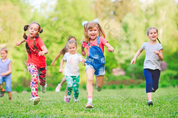 许多不同的孩子，男孩和女孩在阳光灿烂的夏<strong>天一天</strong>休闲服装在公园跑步