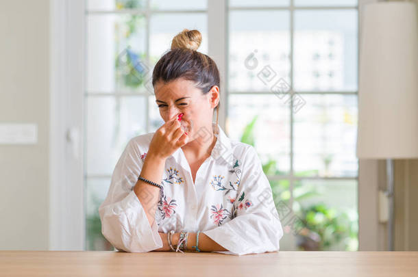 家里的年轻女人闻到了臭味和恶心的气味, 鼻子上握着手指的气息。坏气味概念.