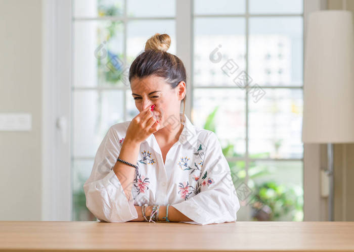 家里的年轻女人闻到了臭味和恶心的气味, 鼻子上握着手指的气息。坏气味概念.