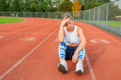 疲惫的女子跑步者坐在跑道上跑步后休息