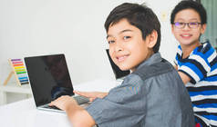 在学校的教室里使用笔记本电脑学习的亚洲学生男孩