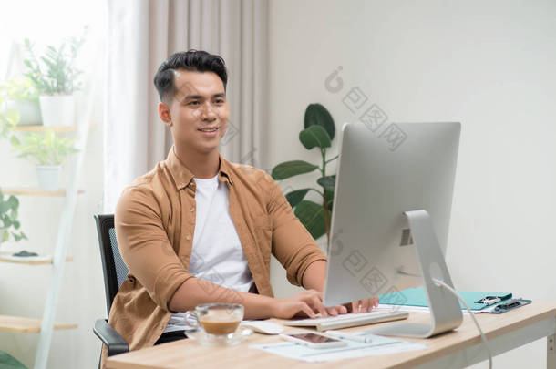快乐的亚洲自由职业者正在他的电脑上工作