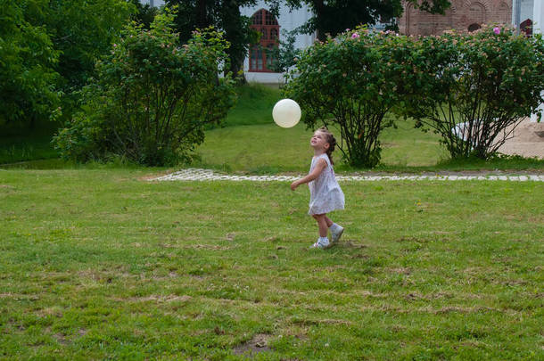 夏天的一天，一个可爱的小女孩和球在公园里玩耍