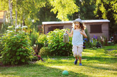 快乐滑稽的孩子女孩在园丁帽子玩浇水罐头在阳光明媚的夏日花园里