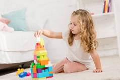 可爱的孩子玩彩色塑料建设者在儿童房的地毯上