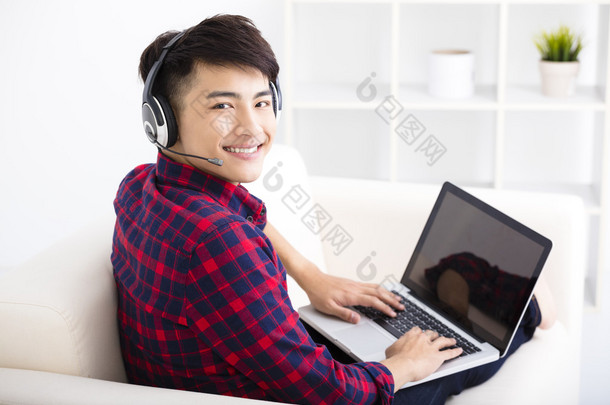 英俊的年轻男子手提电脑用耳机