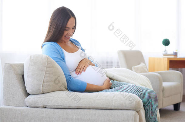 幸福怀孕的女人在家里沙发上休息