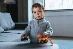 快乐的小男孩在家里的客厅里玩玩具车