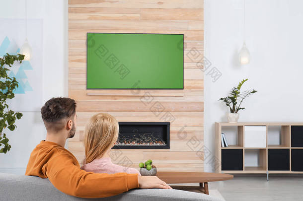 在有<strong>装饰</strong>壁炉的客厅沙发上看电视的情侣