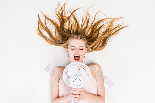 顶部视图的女孩在电风扇喊和遭受热在白色