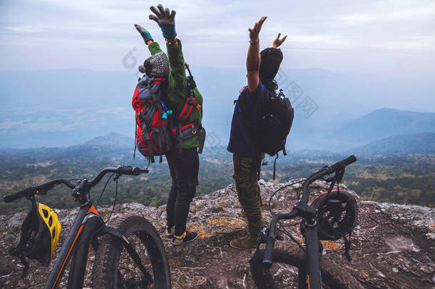  亚洲情人女人和男人旅游自然。旅行放松骑自行车荒野在野外。站在岩石峭壁上泰国 