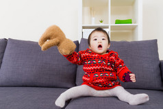 亚洲小女孩在玩布娃娃熊坐在沙发上