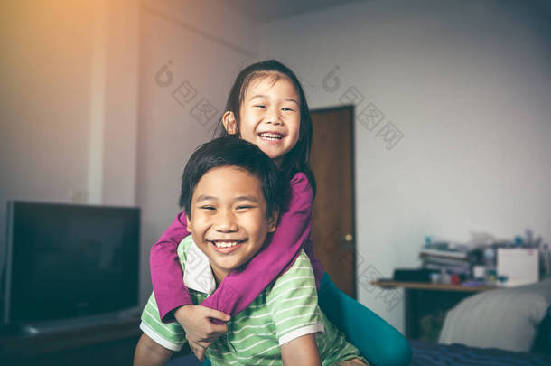 亚洲亲切的兄弟与他的妹妹背着骑和微笑高兴。可爱的孩子们在家里放松。兄弟姐妹概念的爱与结合。复古<strong>胶片</strong>过滤<strong>效果</strong>色调.