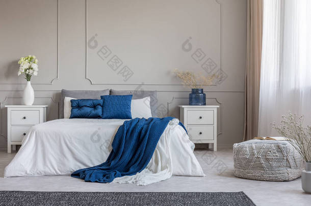 在时尚的灰色白色和蓝色卧室内部的空灰色墙上复制空间