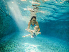 游泳池。妈妈带着她的宝宝在泳池下潜水.