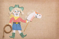 牛仔套在西方的衣服上, 拿着牛的绳索和棍子马玩具。剪纸应用背景文本