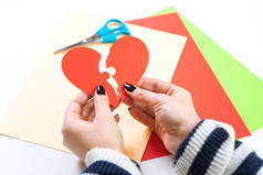 红色心脏拼图。女人的手拿着纸心的两部分。情人节快乐。爱的概念