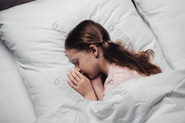 可爱的孩子睡在白色床上用品的顶视图 