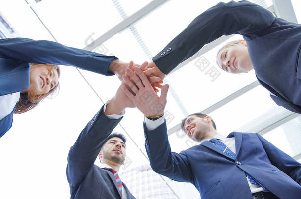 一个由商人组成的小组重叠<strong>成员</strong>的双手以加强团结