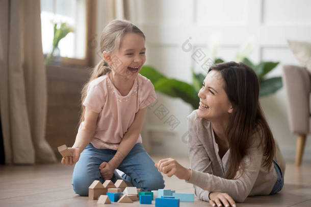 快乐的妈妈和孩子的女儿笑着玩木块