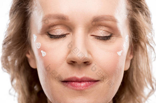 成熟的女人与化妆品<strong>霜</strong>的脸和眼睛关闭孤立在白色