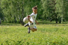 9岁的男孩穿制服在绿色的草地上踢足球。一个孩子用足球踢假球，扔它