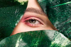 用绿叶把粉色眼罩在眼睛上的女孩的剪影 