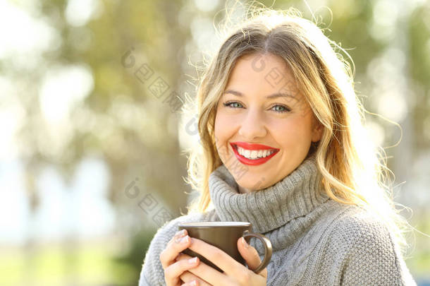 愉快的妇女看在照相机与一杯咖啡