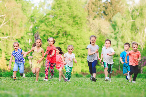 许多不同的孩子，男孩和女孩在阳光灿烂的夏天一天休闲服装在公园跑步