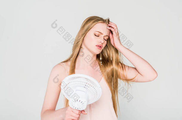 年轻女子遭受热和持有电风扇隔离在灰色