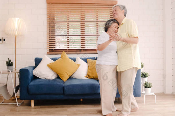 亚洲的一对老年夫妇在客厅里一边跳舞一边听音乐，甜蜜的夫妇在家里放松的时候一边享受爱情的时刻。生活方式老年人家庭在家里放松一下.