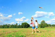 母亲、父亲和女儿正在田野里放风筝。回来了