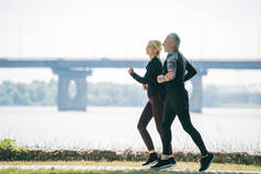 成熟的运动员和女运动员沿着公园河边奔跑
