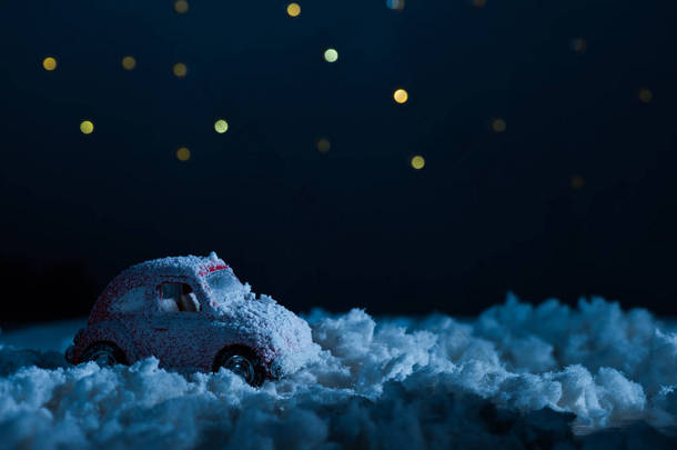 玩具车站在雪中的特写镜头在夜间星空下, 圣诞节的概念