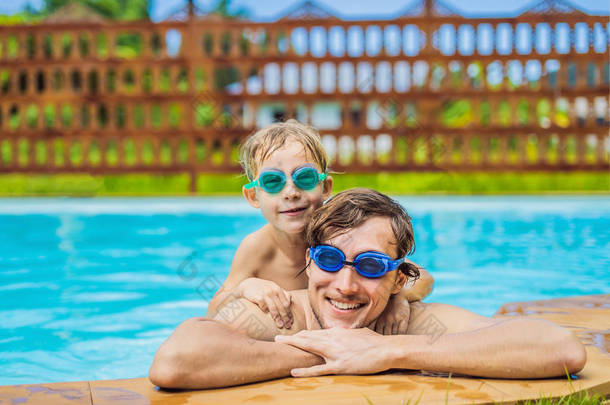 爸爸和儿子在游泳护目镜有乐趣在游泳池里
