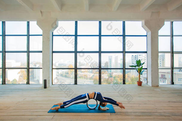 瑜伽在一个大的全景窗户前进入室内. 体育娱乐活动。 漂亮的年轻女子在瑜伽姿势。 个人体育.